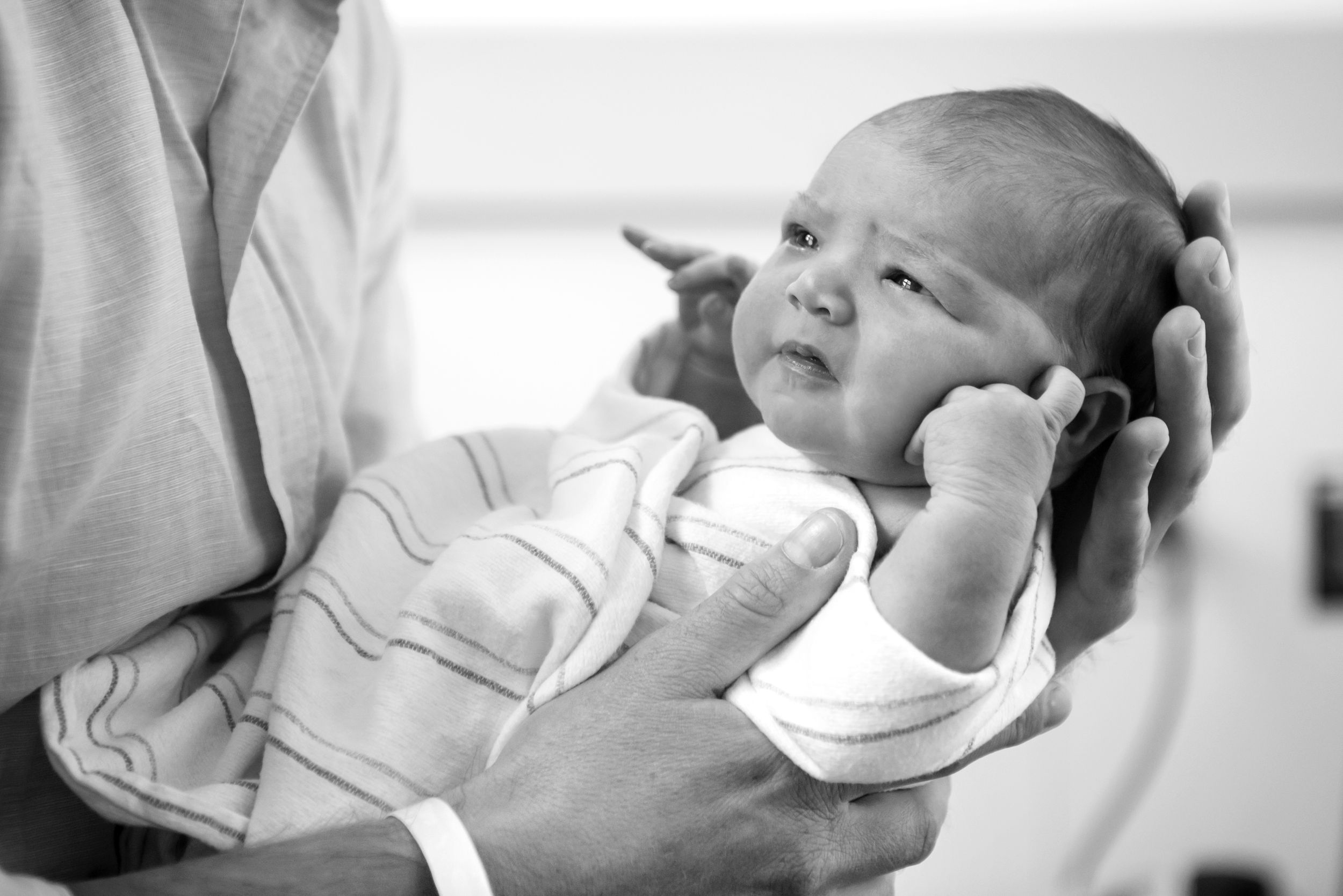 Newborn baby held in father's hands. Captured in a Fresh 48 Documentary Session by Heidi Harting Photography in Plymouth