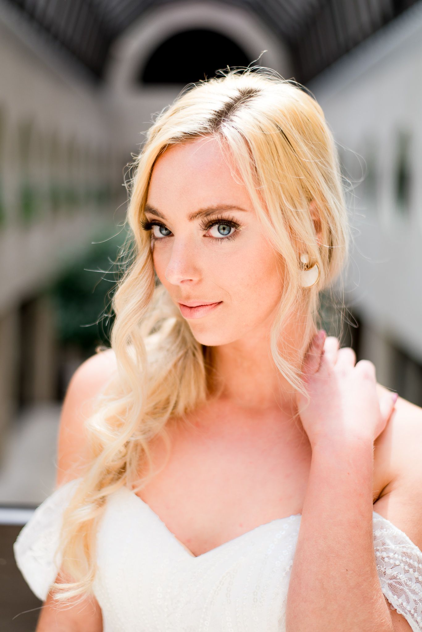 blue eyed blonde bride looks into camera and puts her hand on her neck