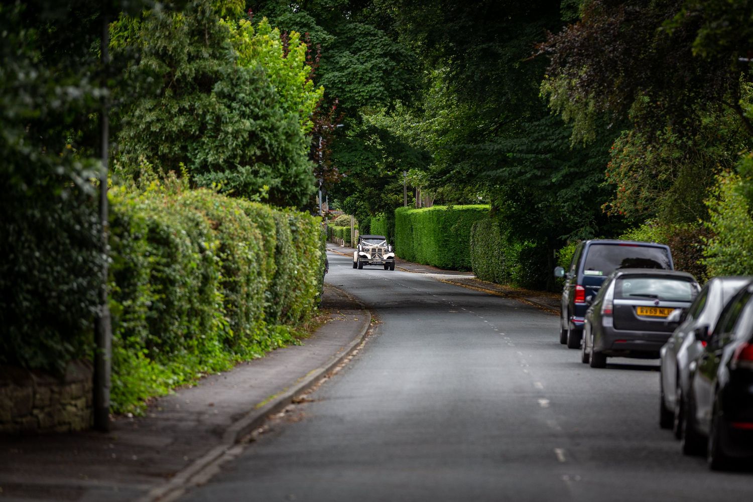Wedding car drives down the country lane bring in the bride
