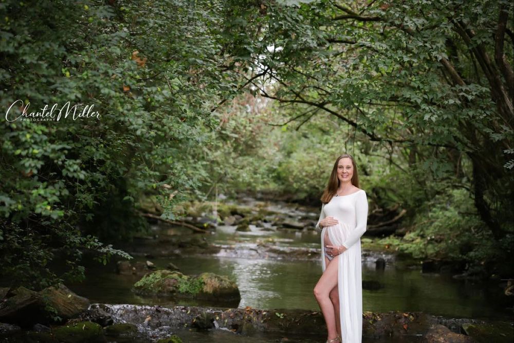 Maternity dressed in white standing in creek