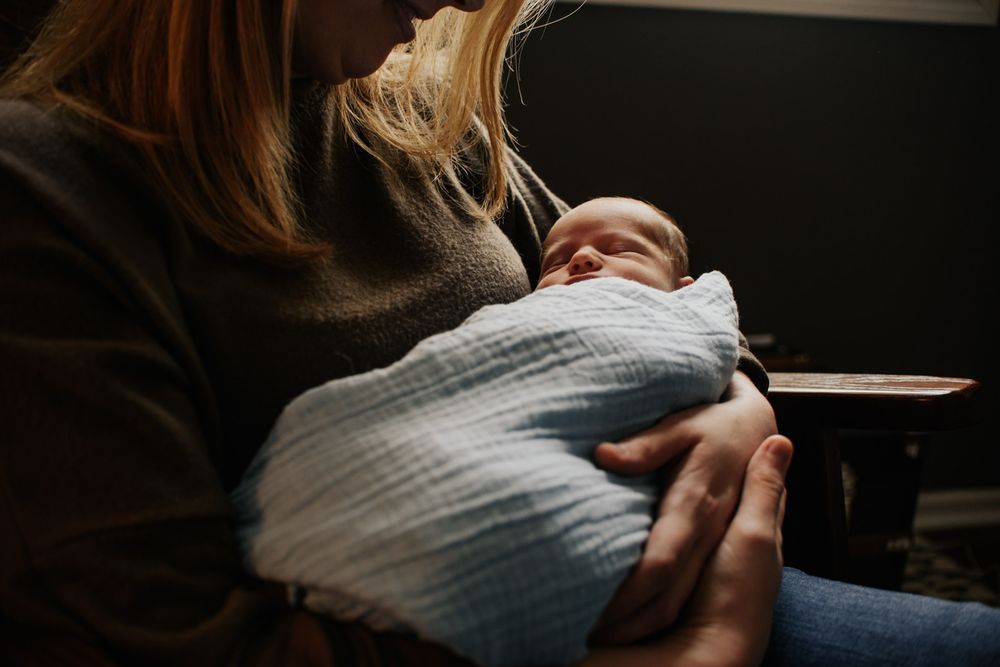 Vanourny Newborn Session Lifestyle Kansas City Photography Mother holding newborn baby cradled in her arms sitting