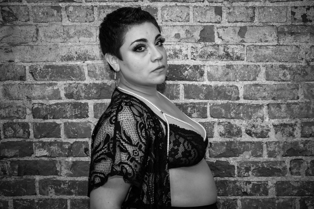 A dramatic black and white boudoir portrait against exposed brick wall.