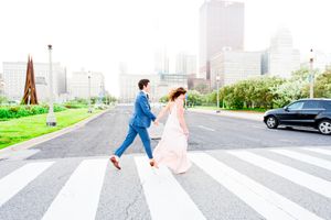 man and woman in suit and dress holding hands running across crosswalk in downtown Chicago Michigan Ave