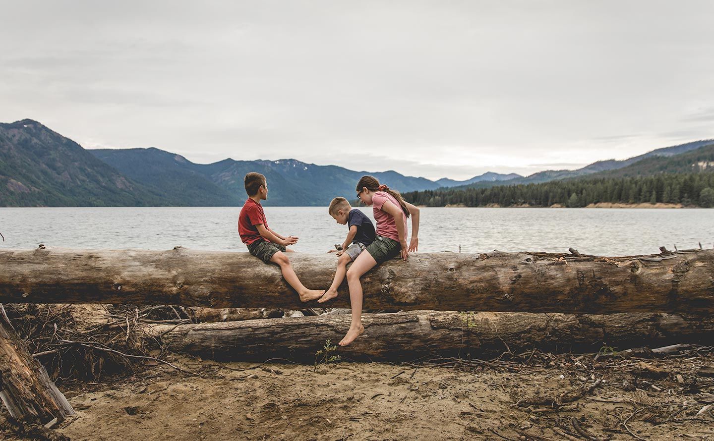 three siblings sitting on log by Cle Elum Lake
