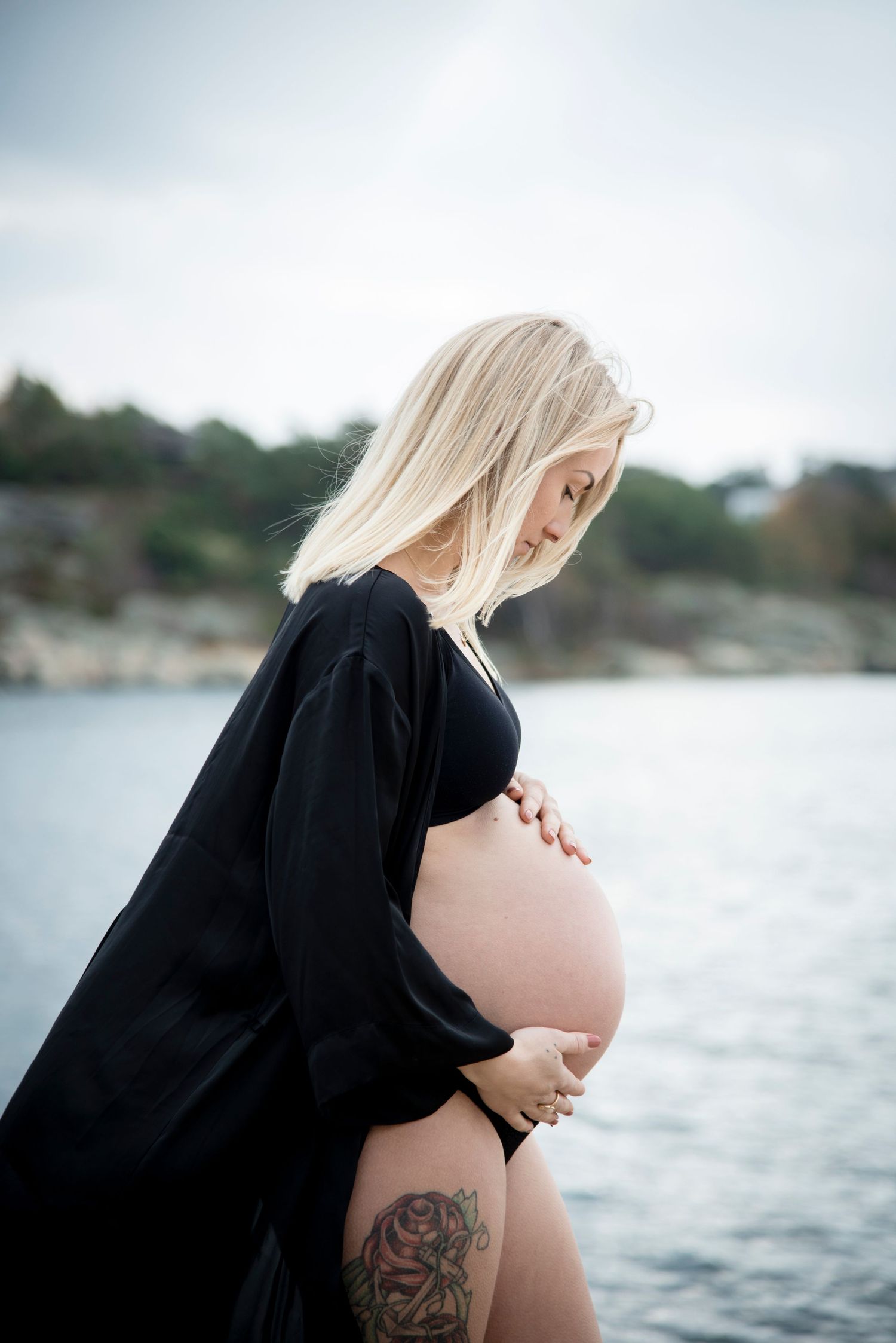 Gravidfotografering vid vattnet med mamma som har tatuering