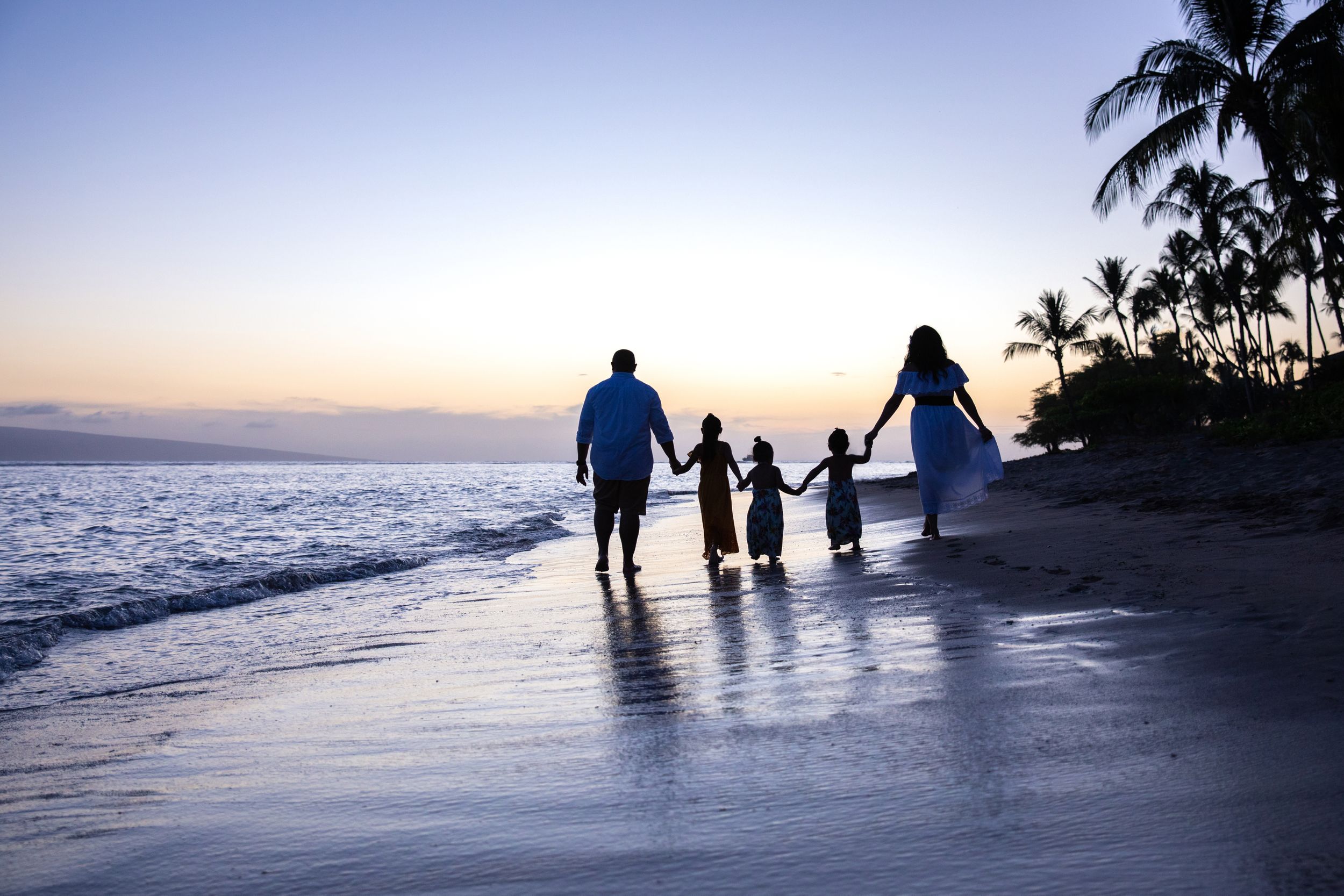 family walking into sunset on beach
