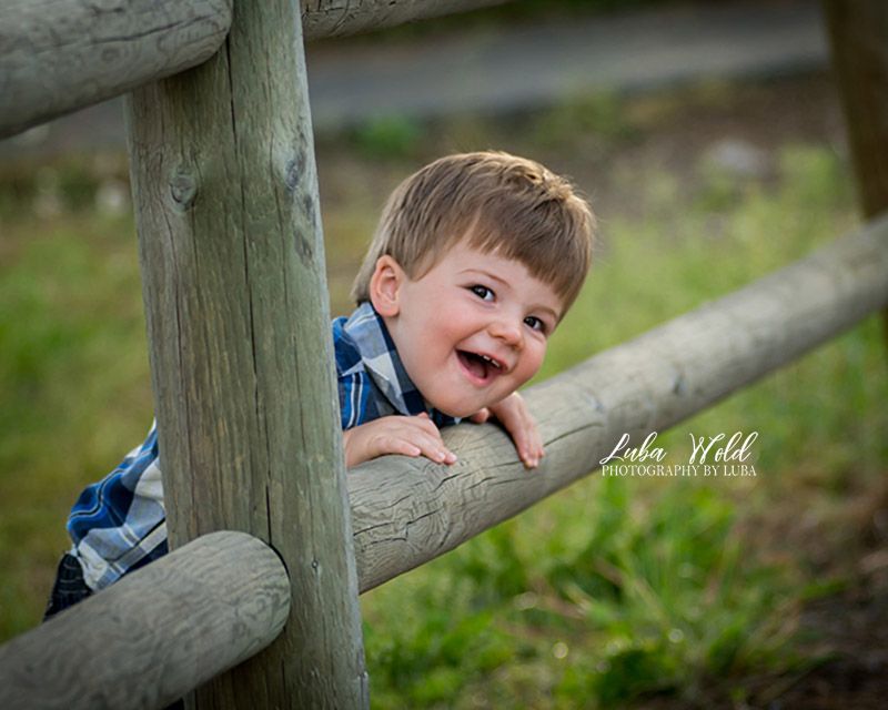 toddler boy picking through fence smiling photographer luba wold spokane