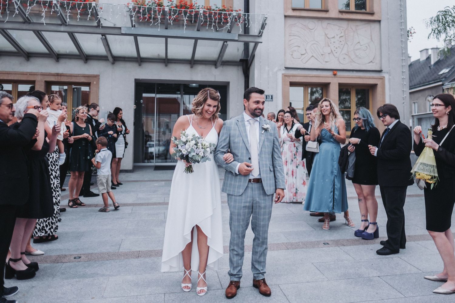 Wedding guests celebrating as newlyweds exit building on their special day.