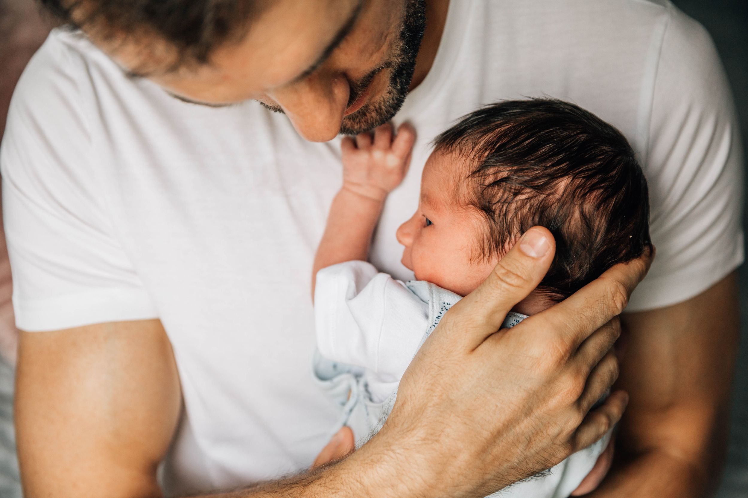 dad holding new born son close to chest