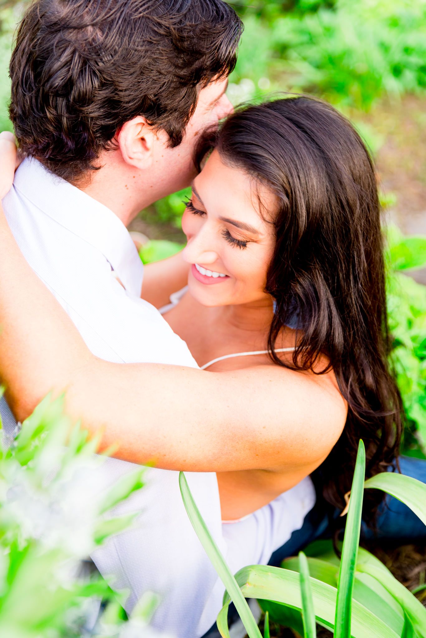 woman with long dark hair hugging fiance and smiling with eyes closed in Lincoln Park gardens