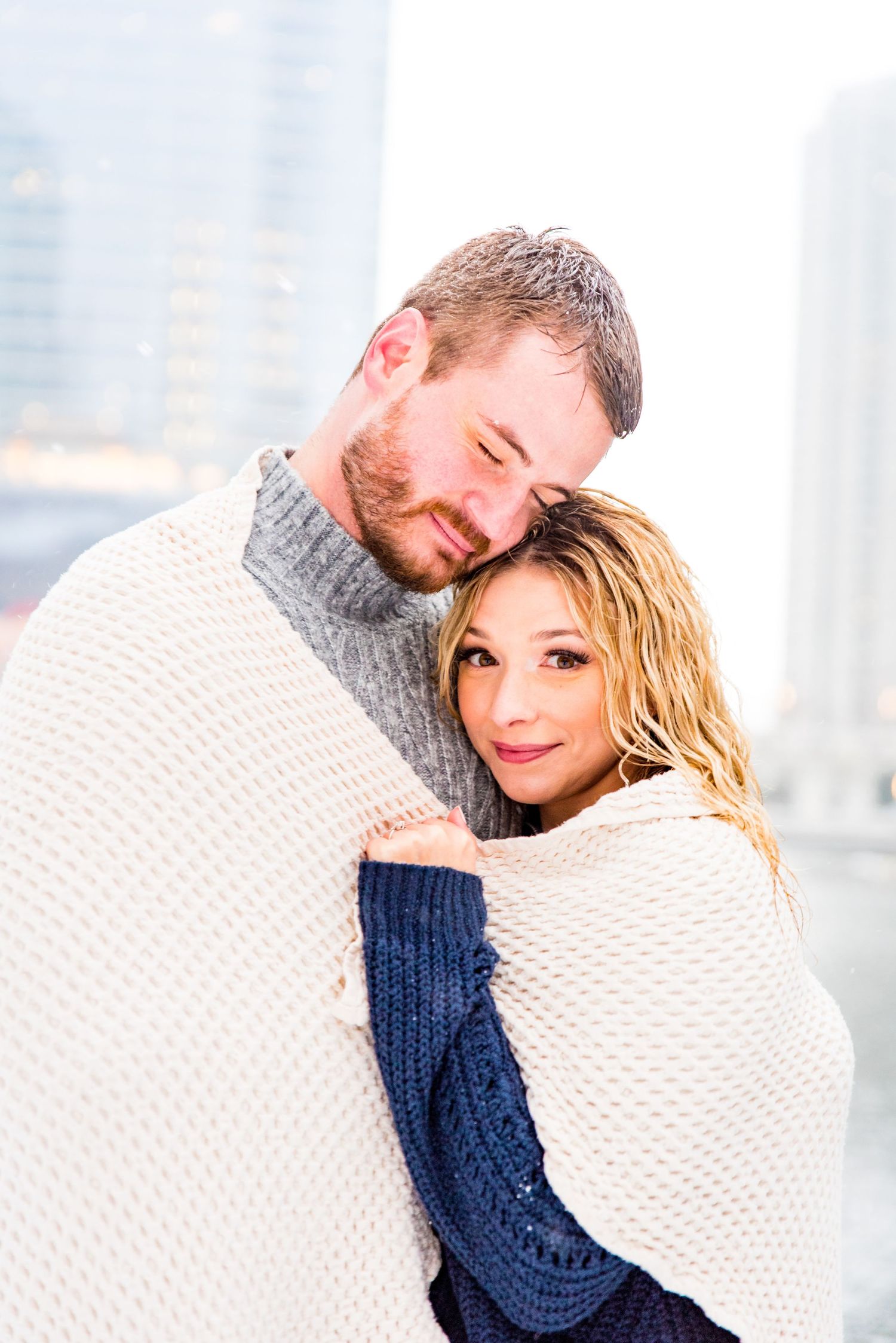 engaged couple wrapped in blanket for snowy Chicago engagement pictures at Wolf Point and Merchandise Mart