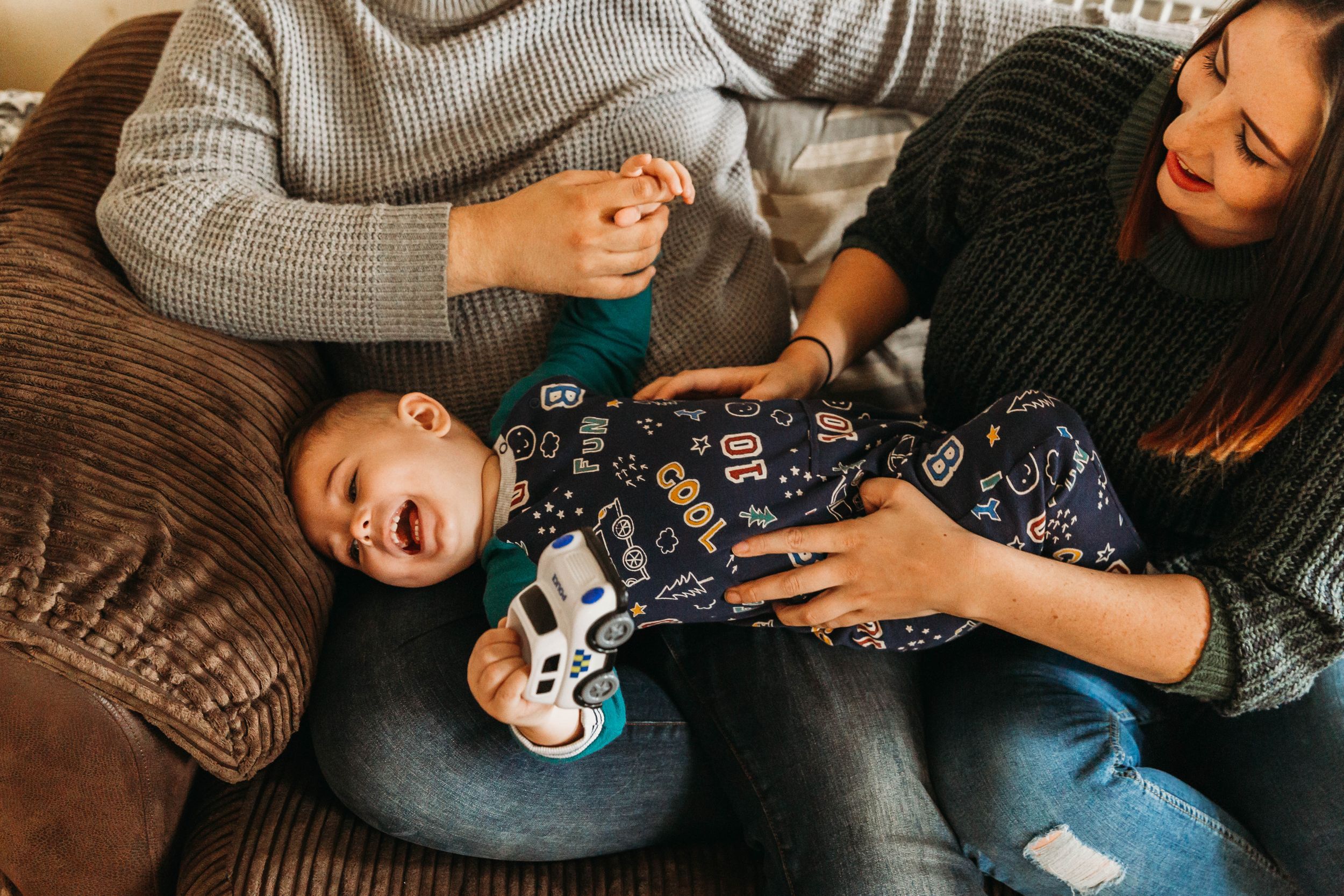 mum tickling little boy on sofa