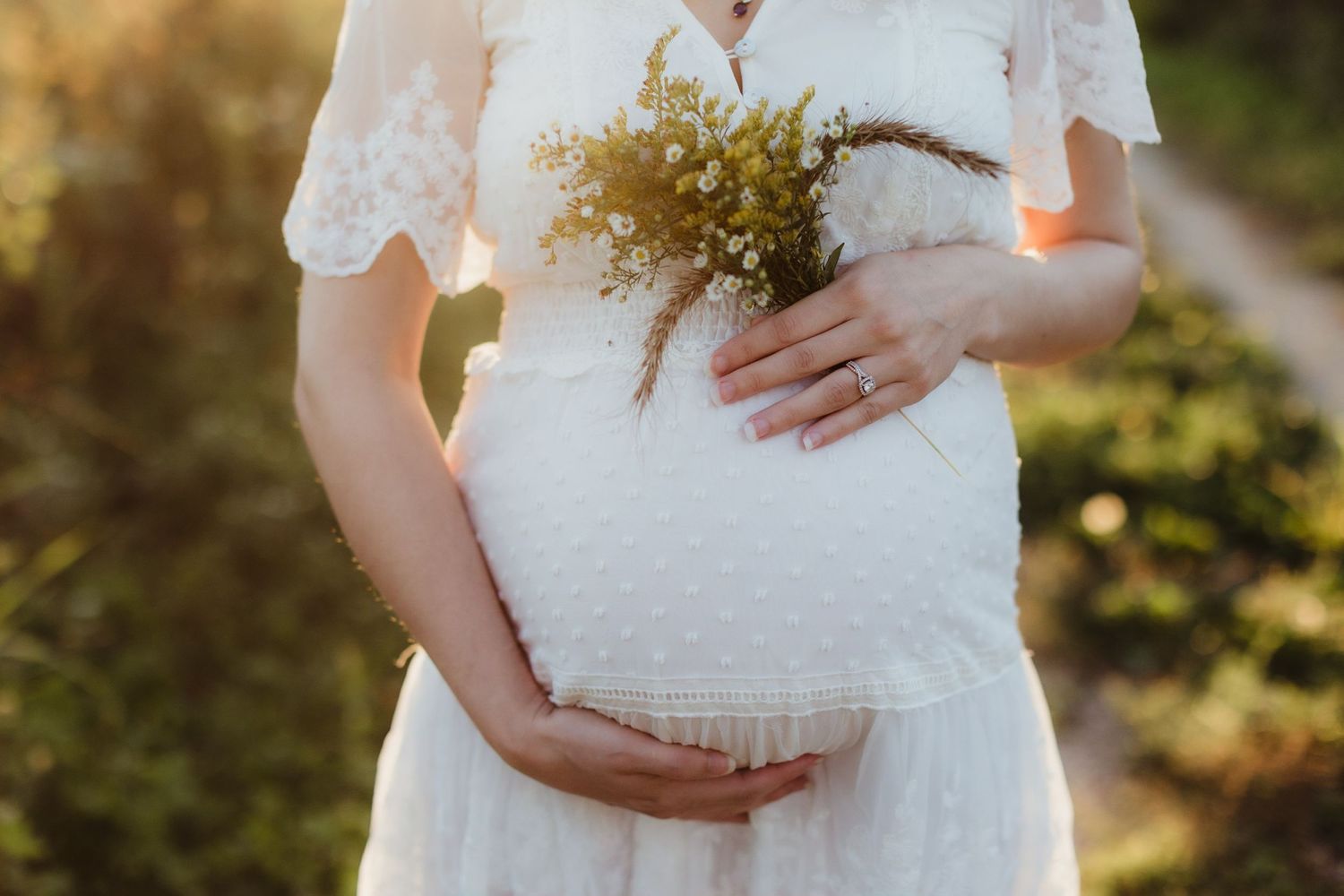 A woman cradles her pregnant belly at sunset. Photo by maternity photographer, Elizabeth Pachniak Photography.