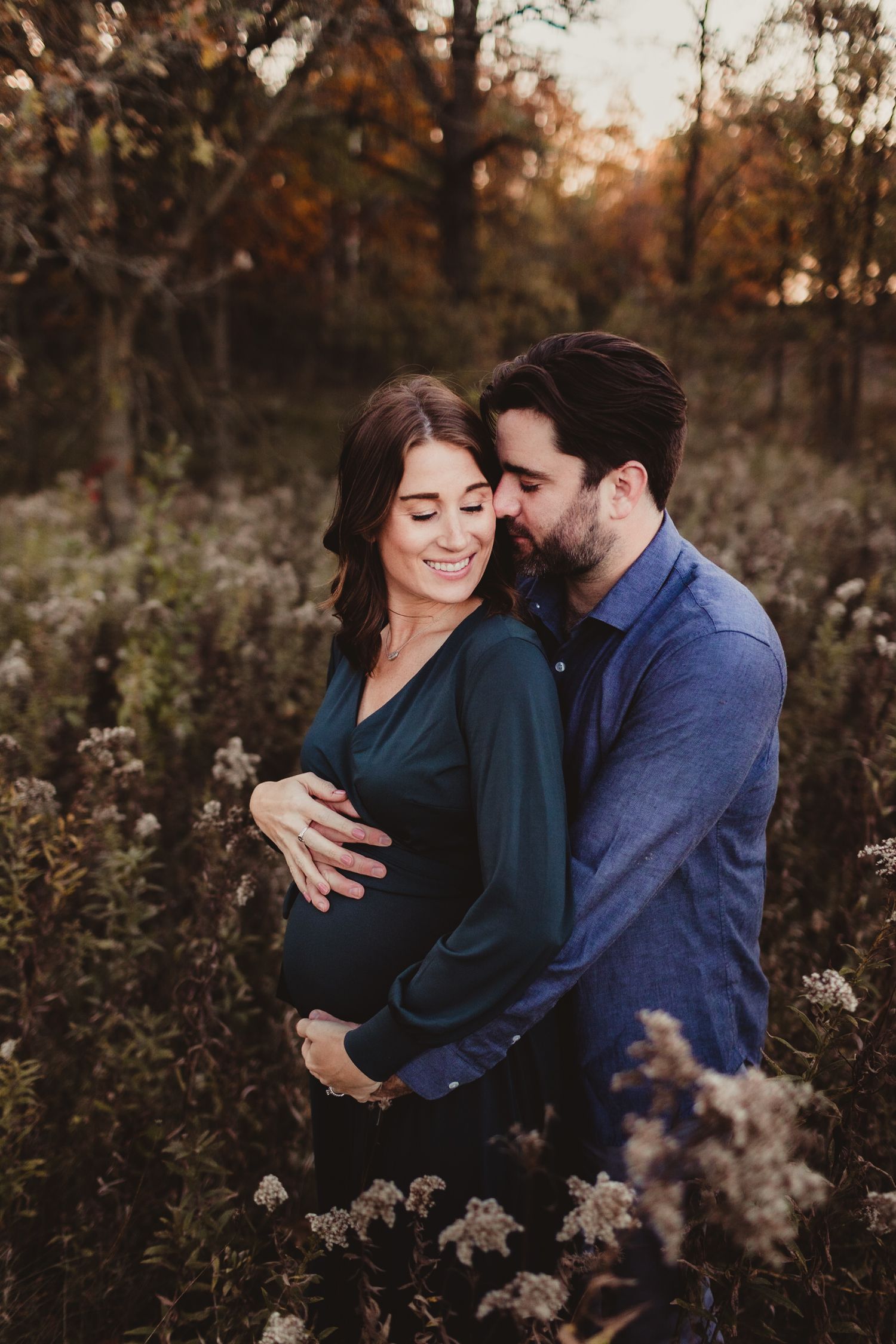 An expecting mom and dad cradle moms pregnant belly at sunset. Photo by maternity photographer, Elizabeth Pachniak.