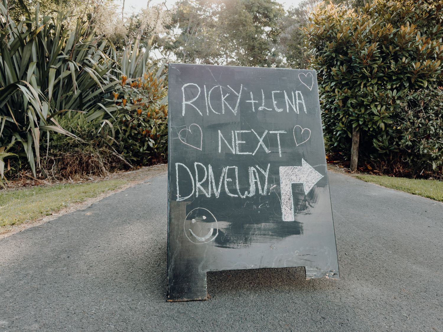 Chalkboard sign on pathway advertising drive-in with handwritten text and arrow.