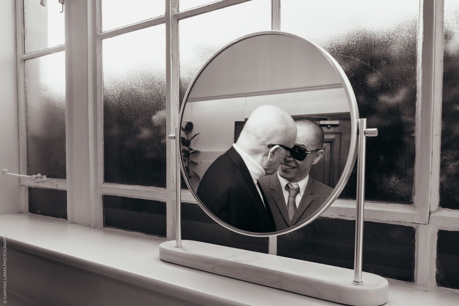 Mirror in front of a window showing a newlywed gay couple looking at each other in Islington Town Hall in London