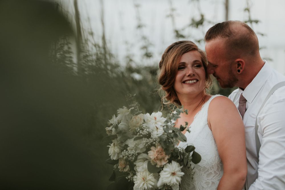 Bride and groom sharing whispers in the rows of hops