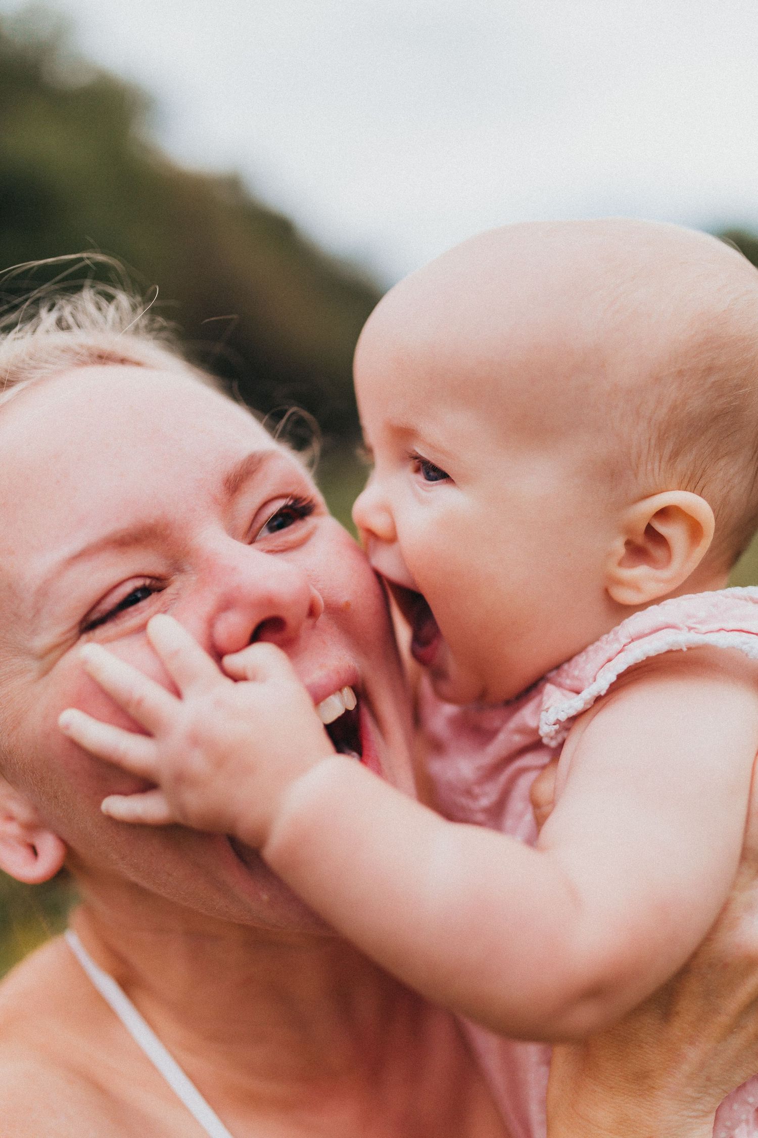 Joyful intimate moment between baby in pink outfit and caregiver during playtime.