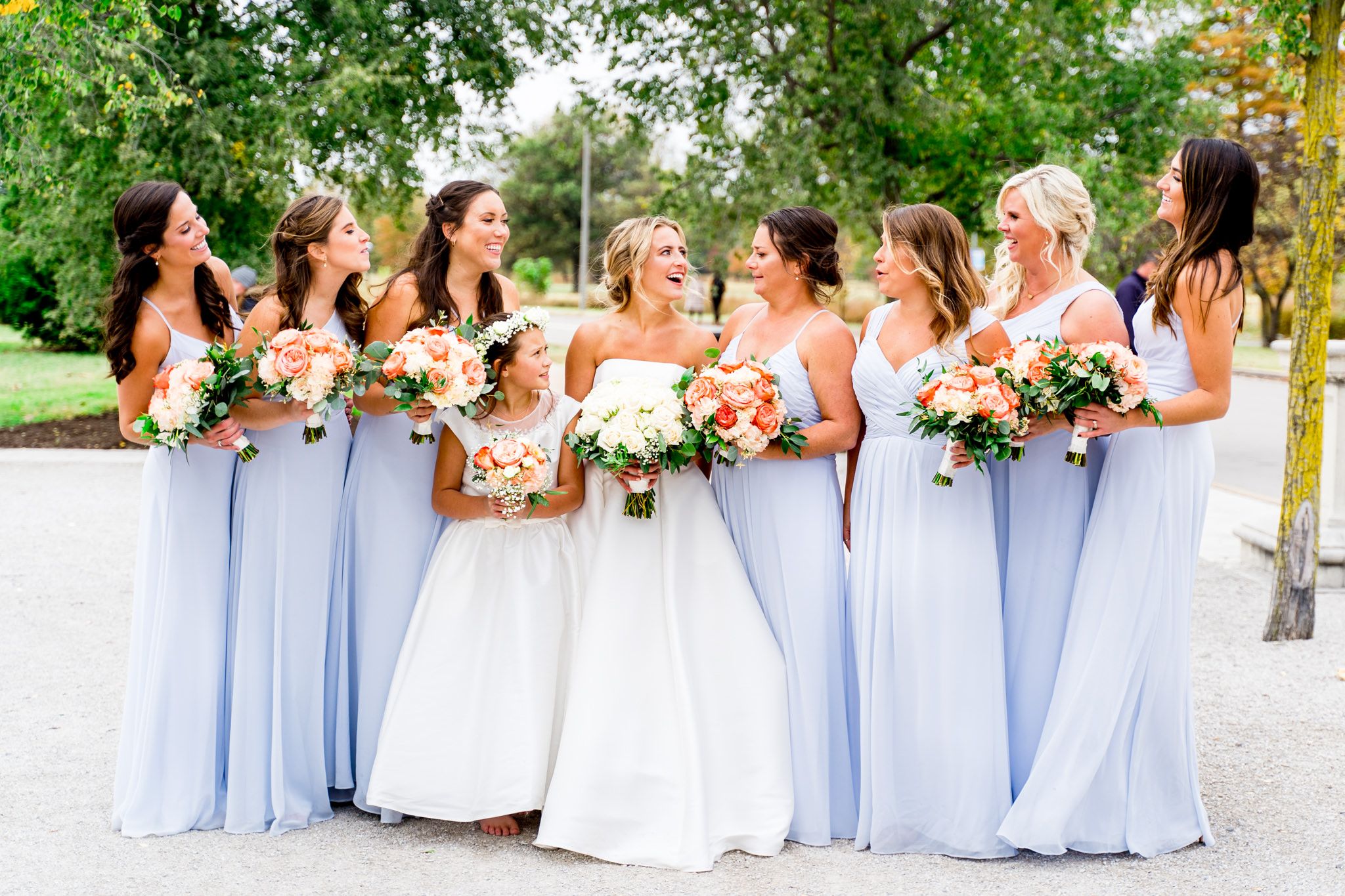 bride laughs with bridesmaids in light blue dresses and coral bouquets at STL Forest Park fall wedding