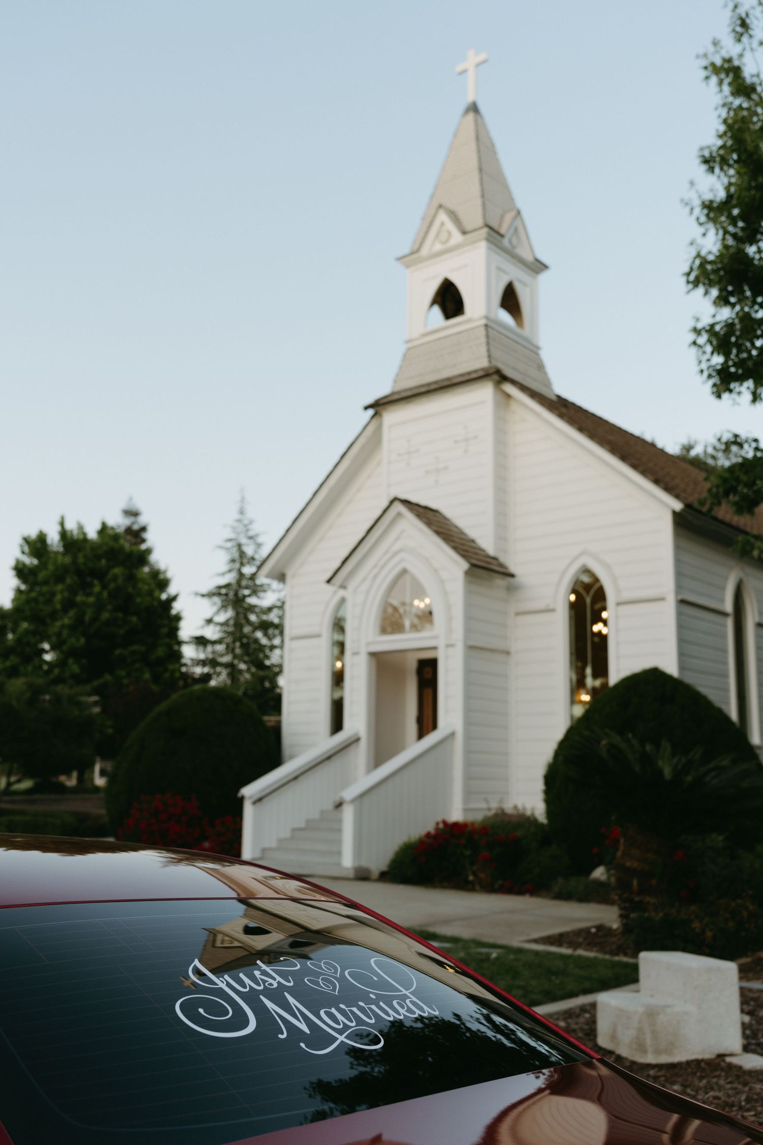 A classic white country church with a tall steeple against a blue sky.