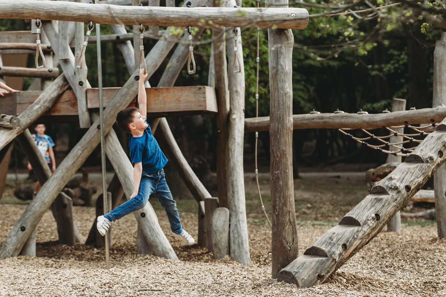 little boy smiling climbing monkey bars in playground