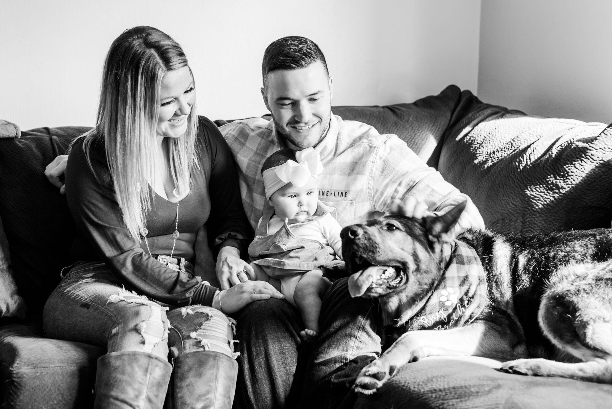Lifestyle family photoshoot in the home with mom, dad, baby, and dog sitting on couch in Gibsonia, Pennsylvania