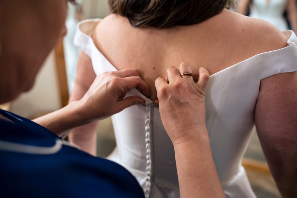 mother of the bride buttoning wedding gown