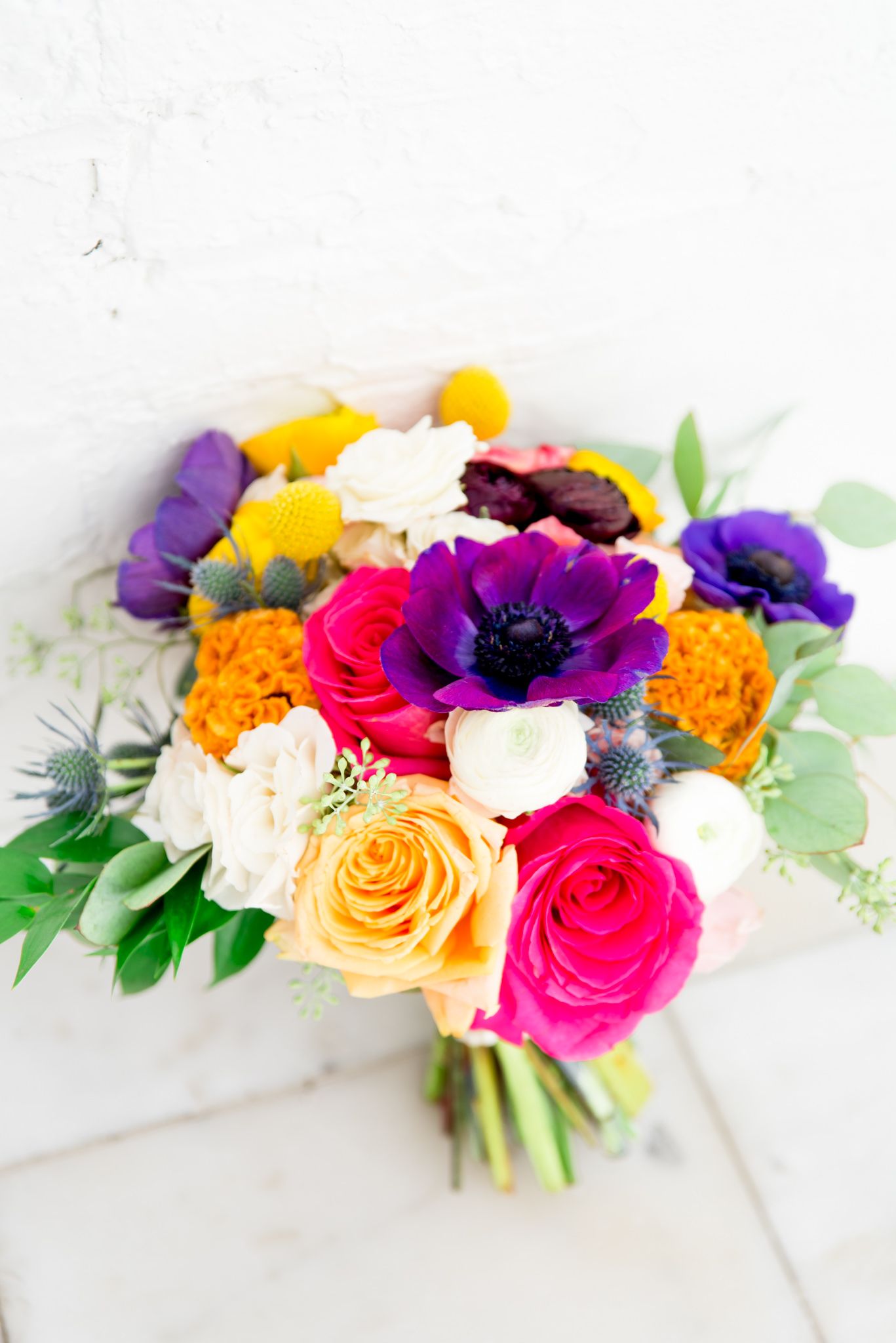 colorful wedding bouquet with purple anemone, pink roses, blue thistles, eucalyptus, and marigolds for a Chicago wedding