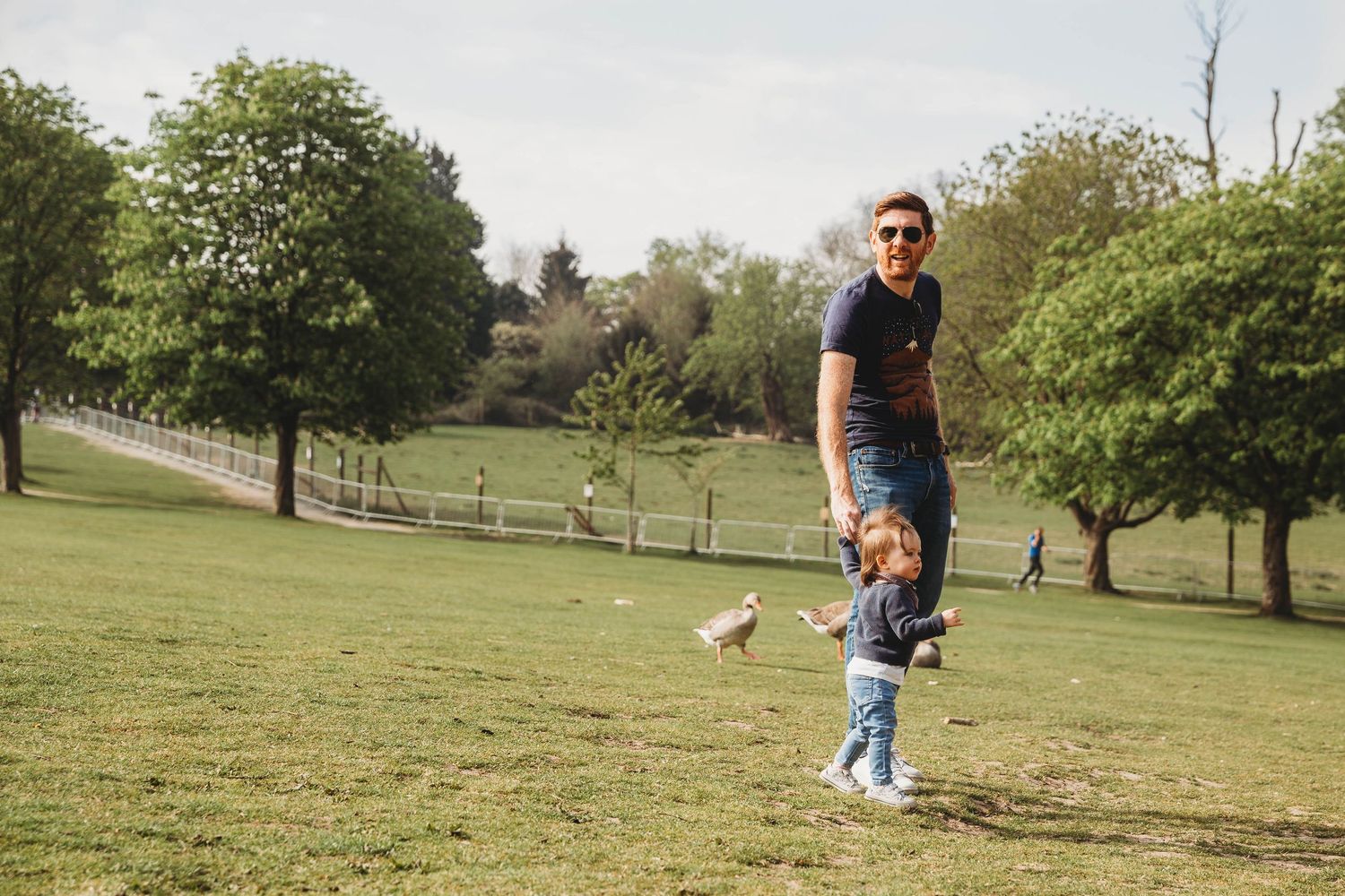 man holding little girl hand in park