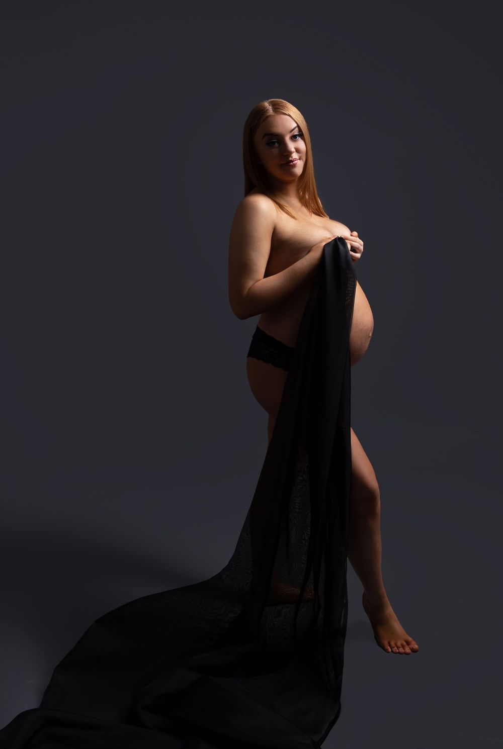 pregnant lady holding black material to cover herelf