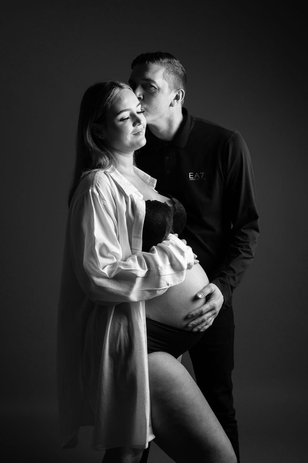 pregnant lady being kissed by partner holding bump