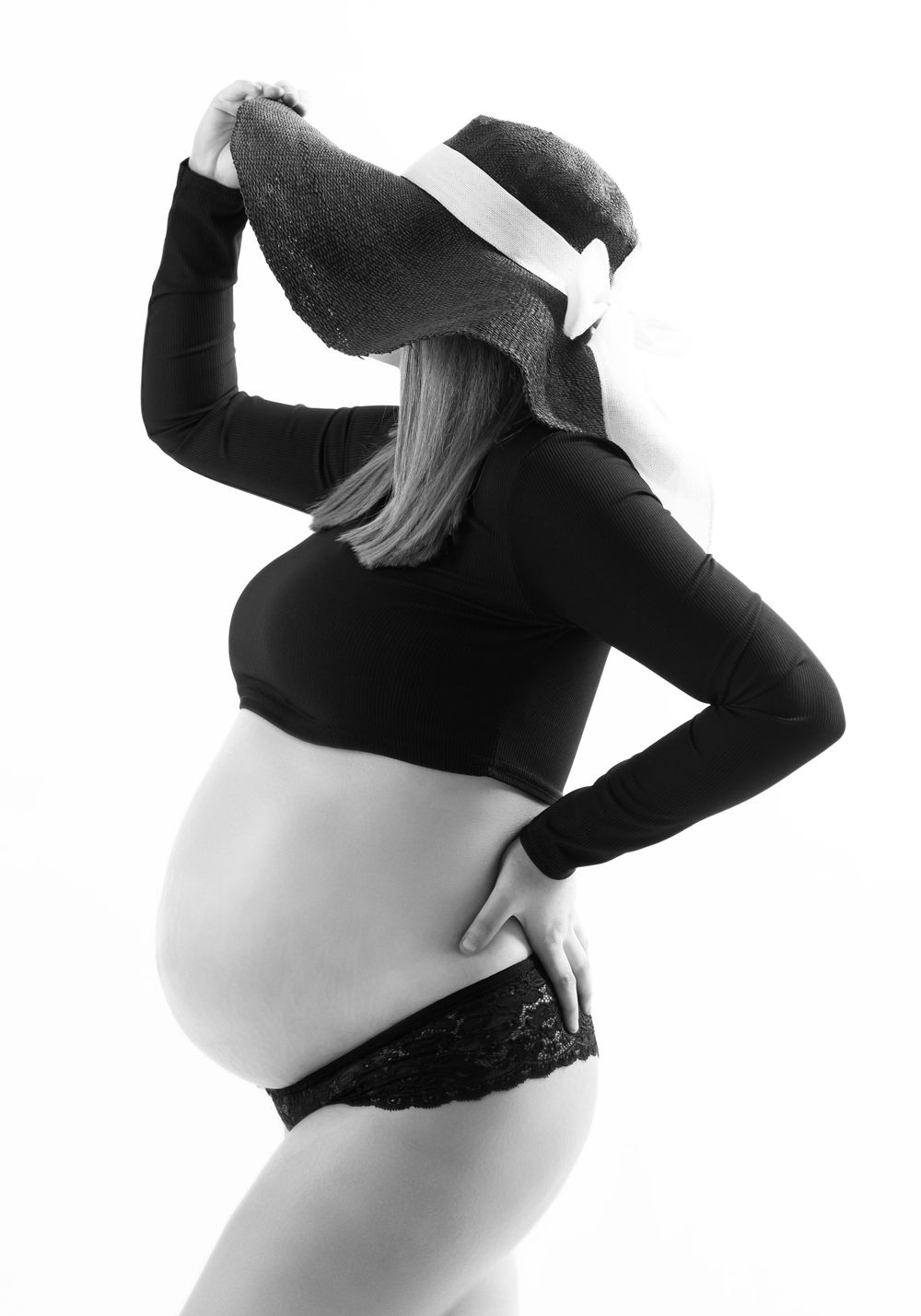 pregnant lady with black short black crop top and black sunhat