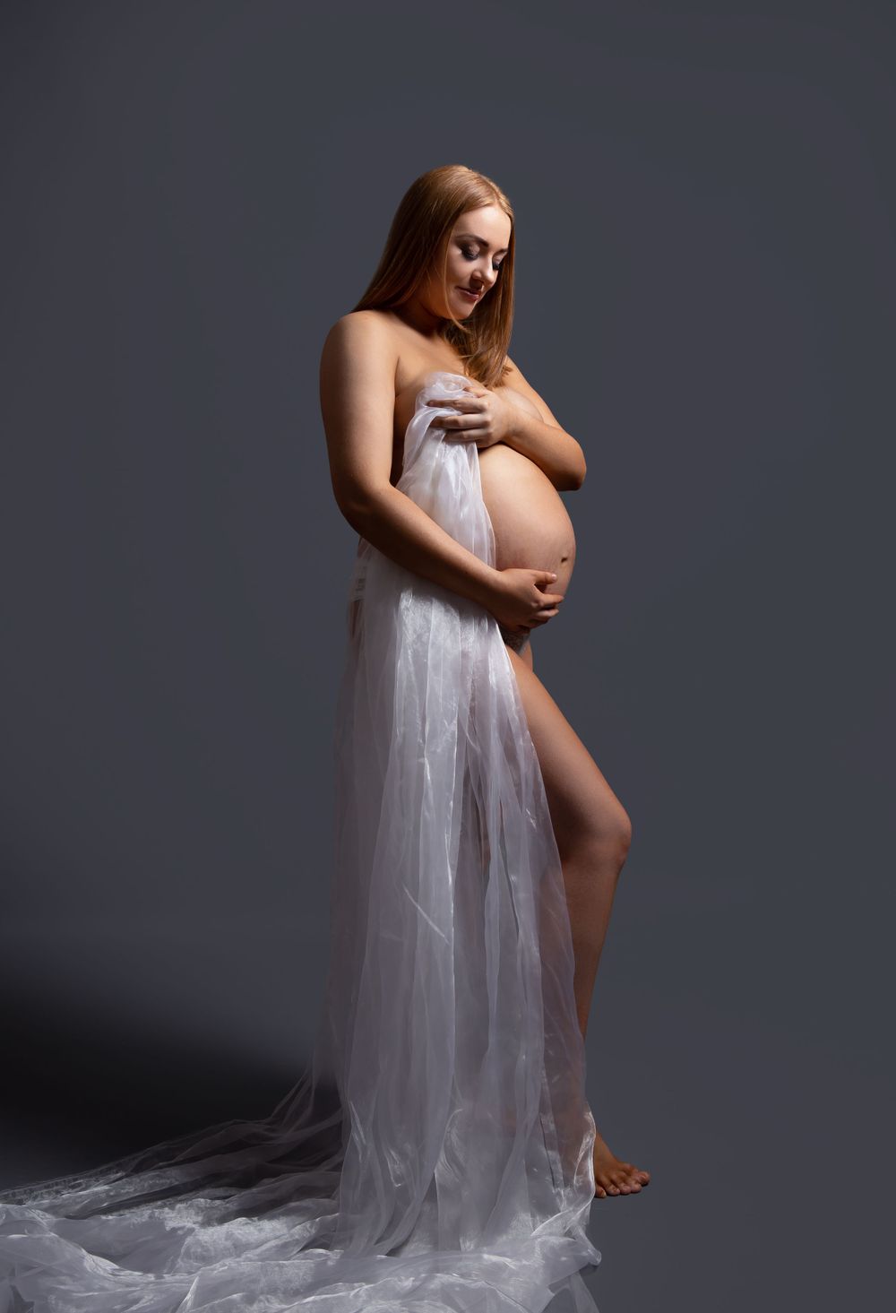 pregnant lady holding material to cover herself