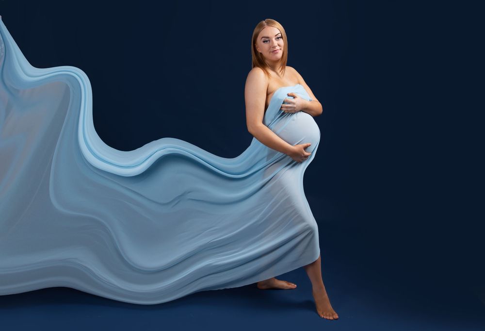 pregnant lady covered in blue material that is flowing