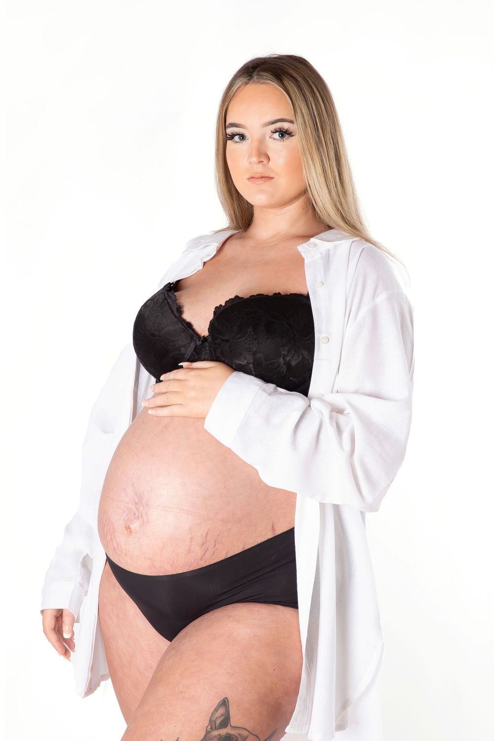 mum to be in black underwear with a white shirt over with hand on bump