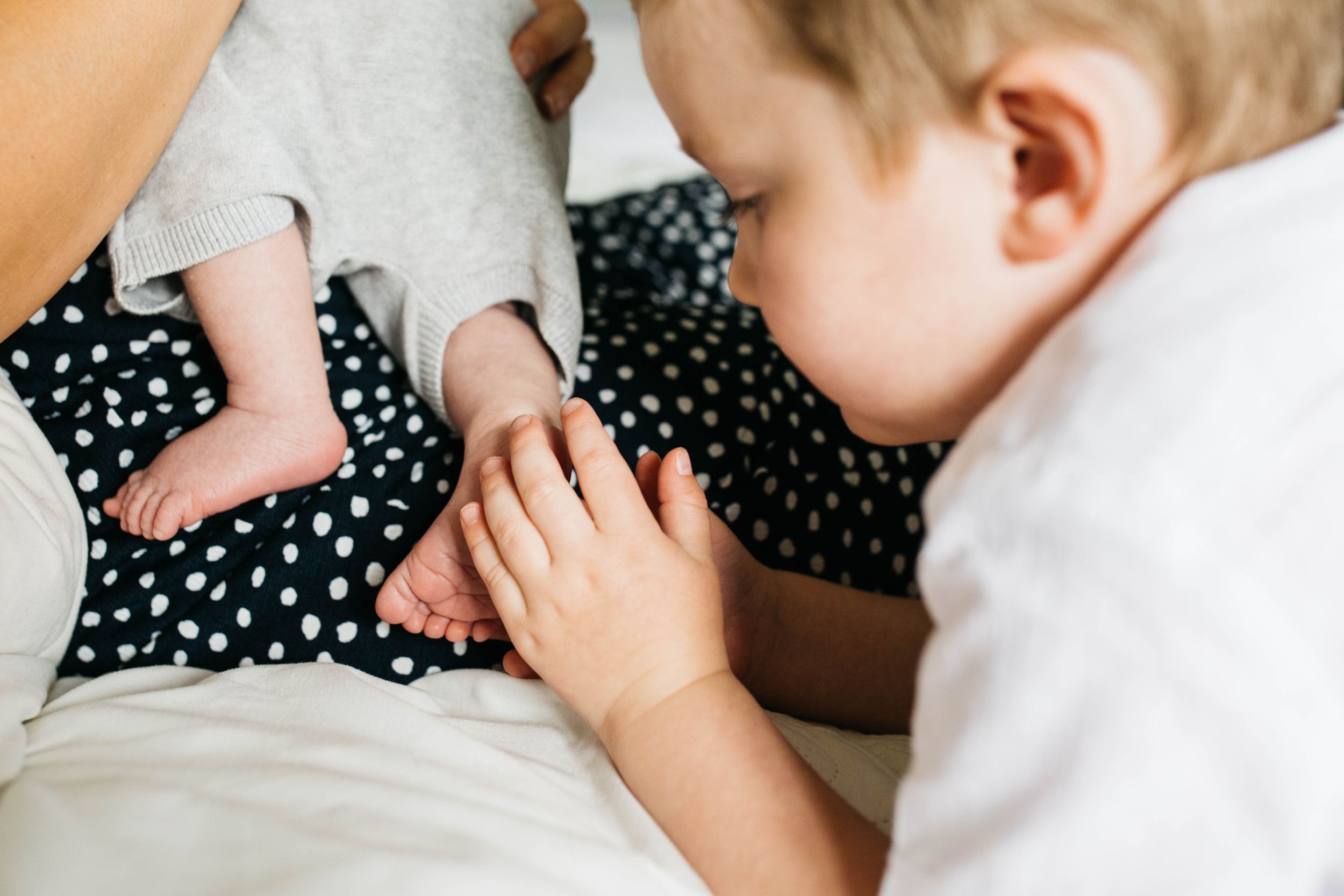 big brother caressing baby brother foot