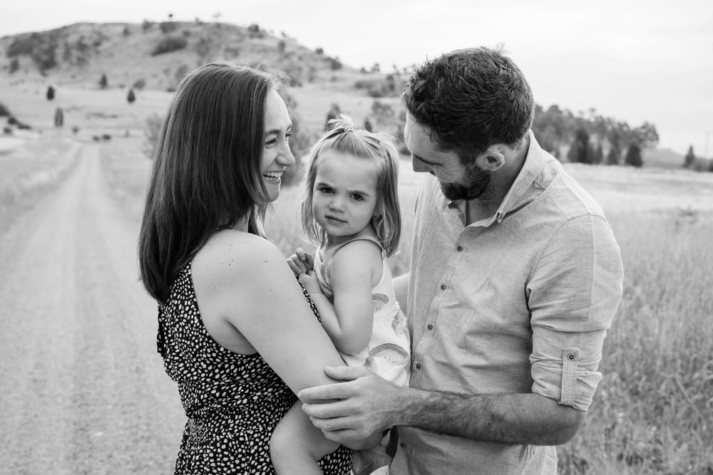 A black and white portrait of a family sharing an intimate moment on a country road.