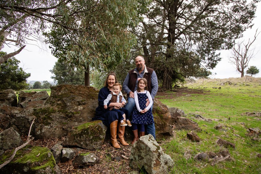 Family sits together on fallen tree during outdoor photo session.