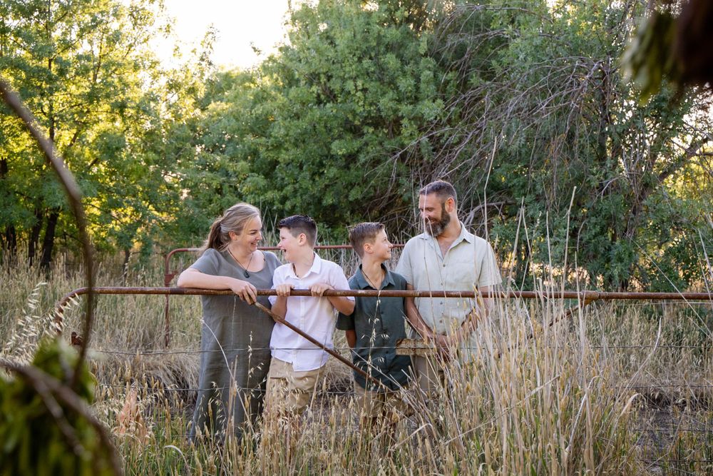 A group stands together on a nature path amid tall grasses and trees during golden hour.