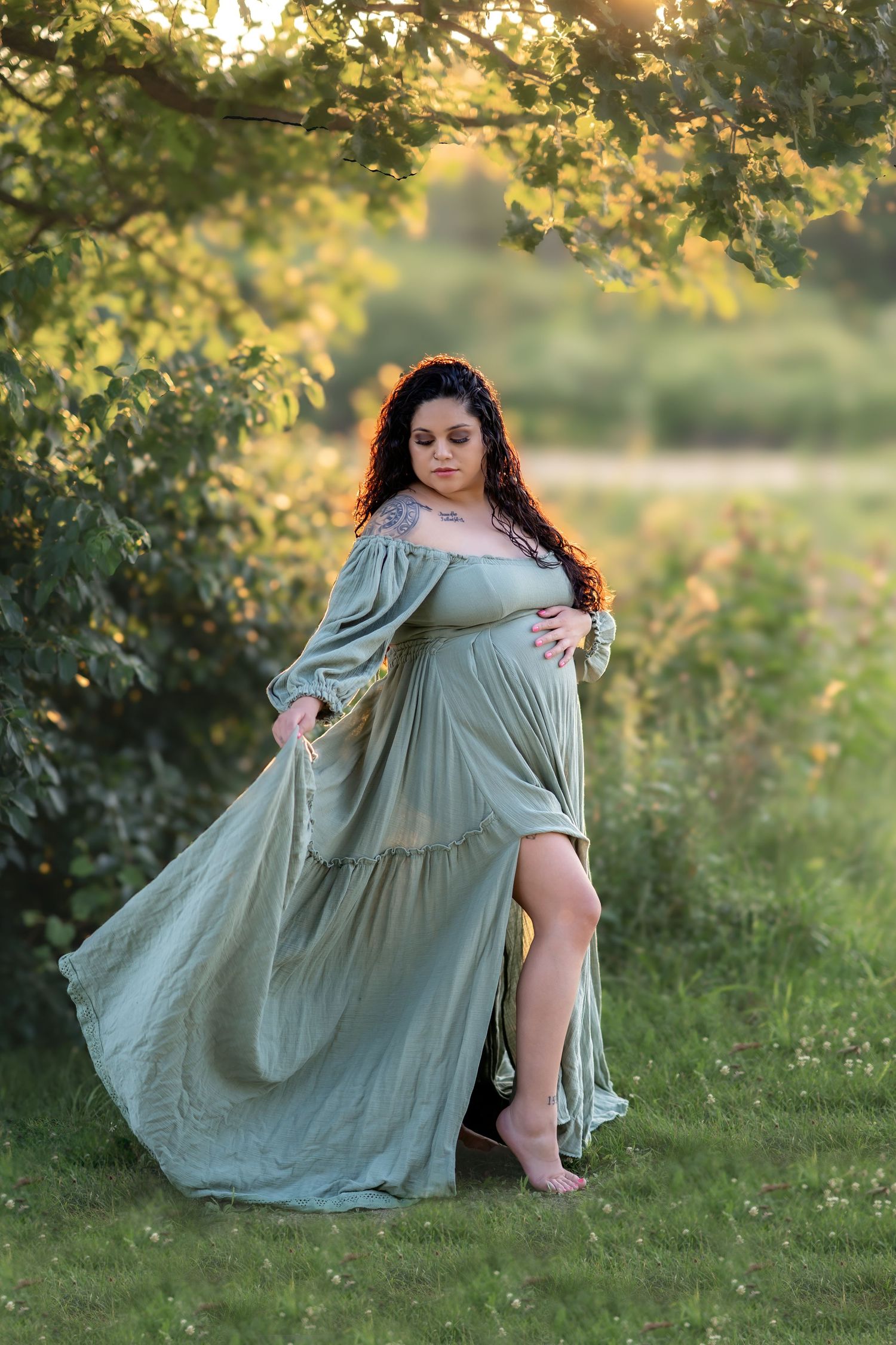 Flowing sage green maternity gown captured in romantic outdoor sunset photoshoot.