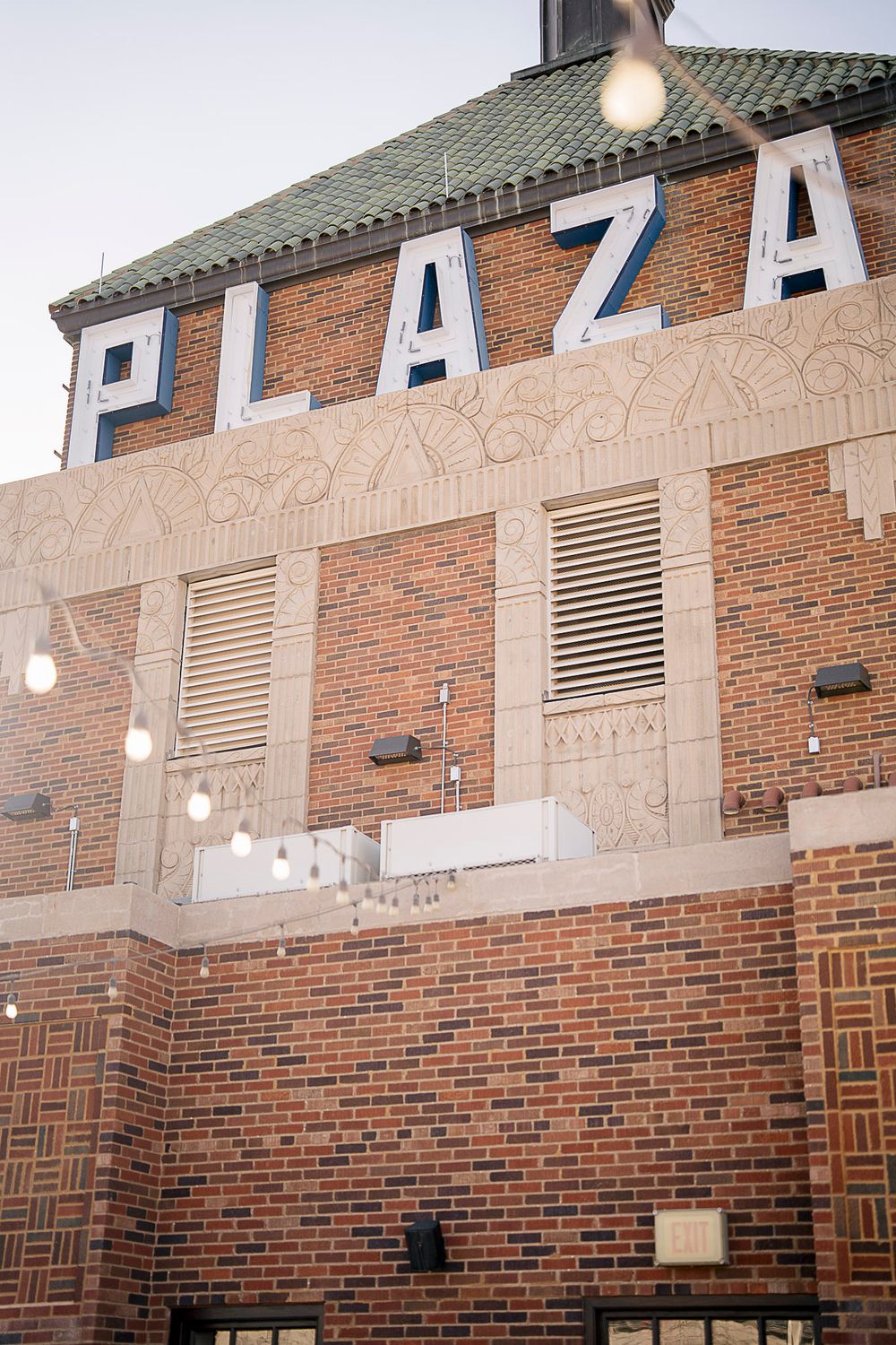 Exterior view of a brick building with large 'PLAZA' letters mounted on the upper facade.