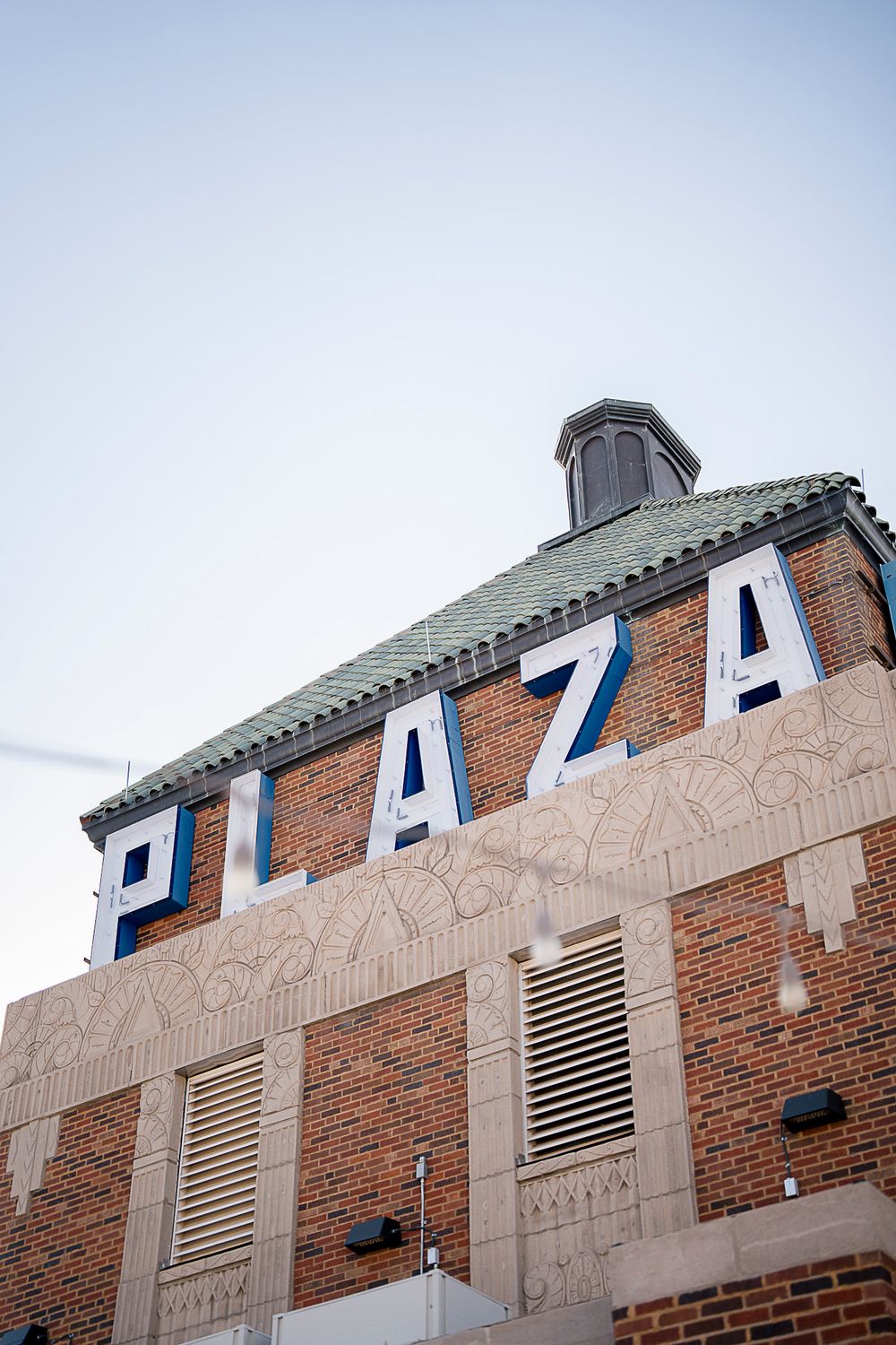 Architectural detail showing a series of blue and white letters mounted on a brick and concrete building facade.