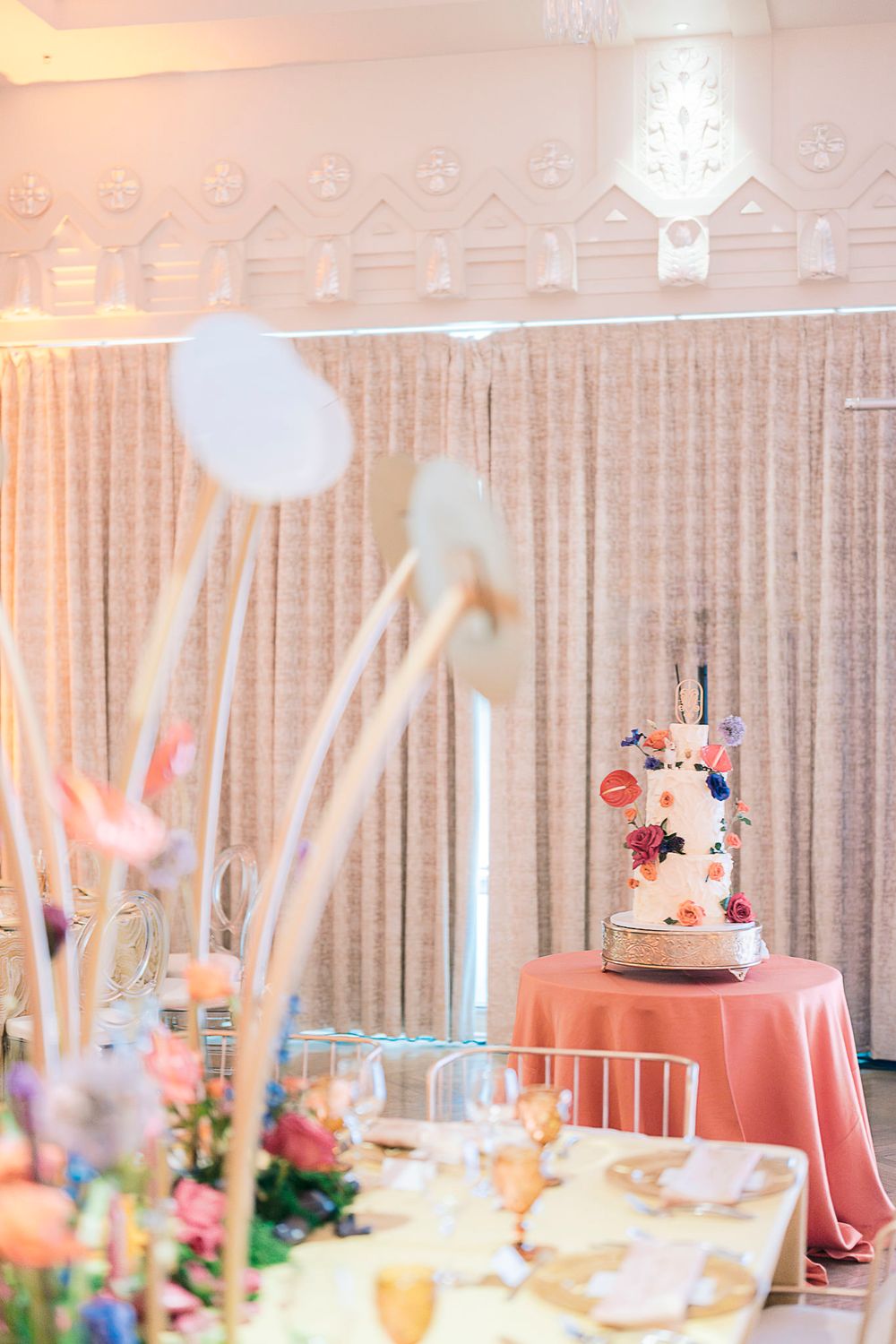 Elegant wedding reception table with pink linens and floral decorations featuring a delicate three-tiered cake.