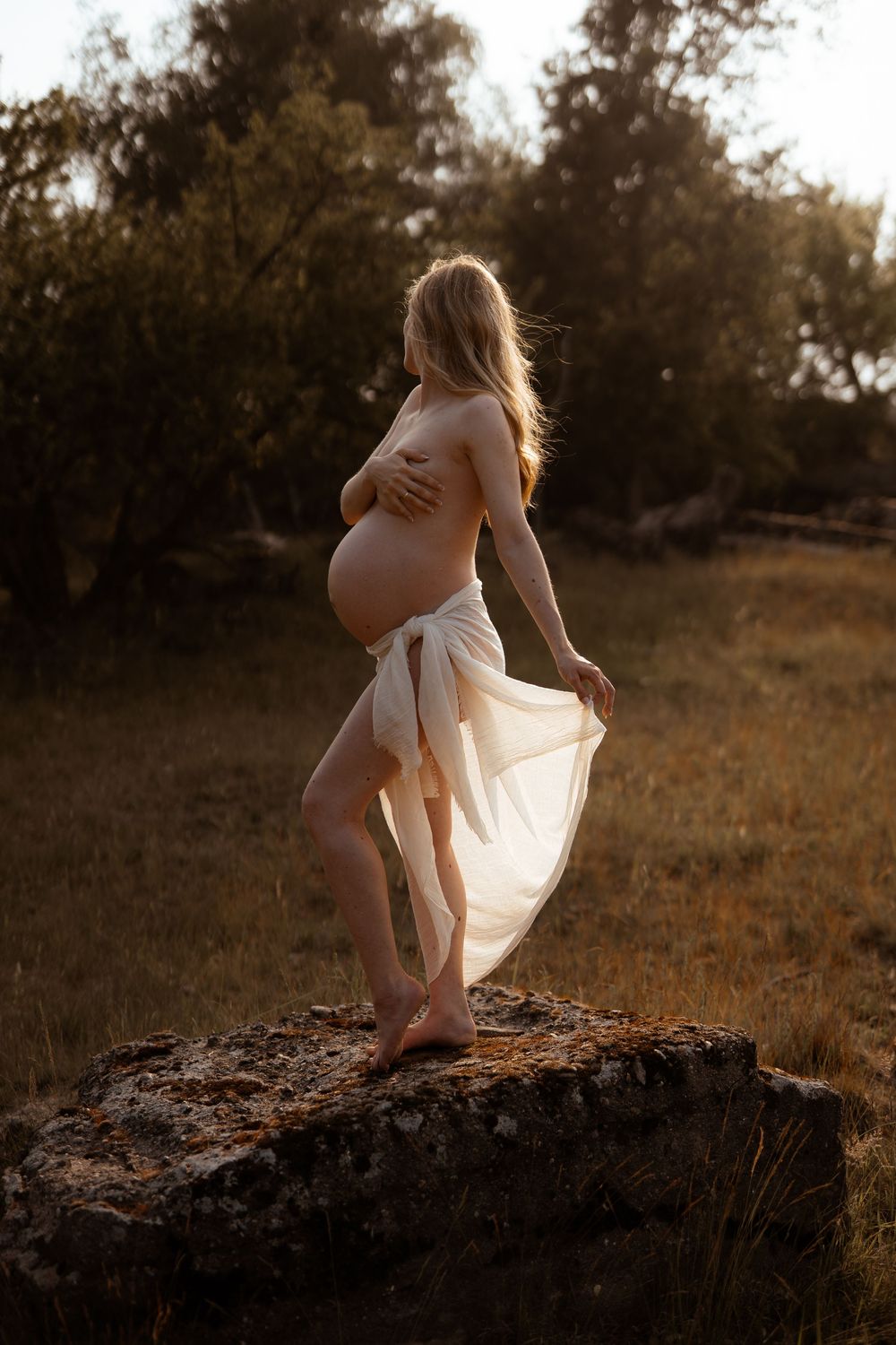 A silhouetted maternity photo shows an expectant figure in flowing fabric against a golden sunset backdrop.