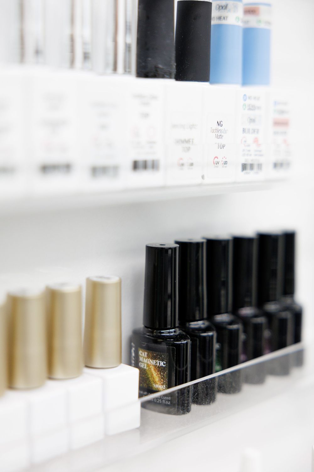 A line of cosmetic or beauty product bottles arranged in a row on a white shelf with selective focus.