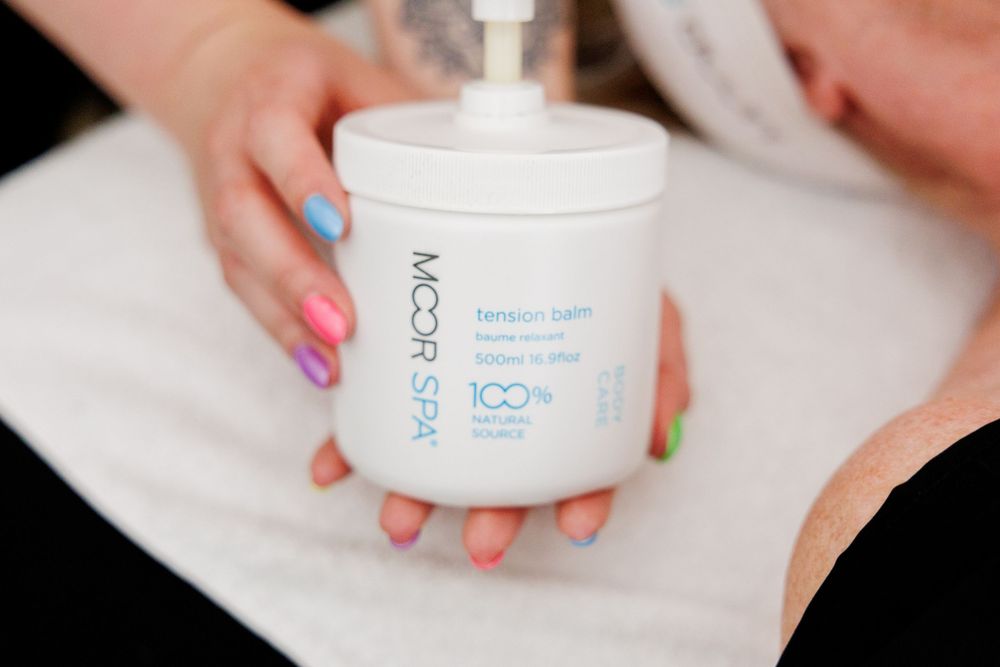 White skincare product jar with ICO branding shown from multiple angles with colorfully manicured nails holding it.