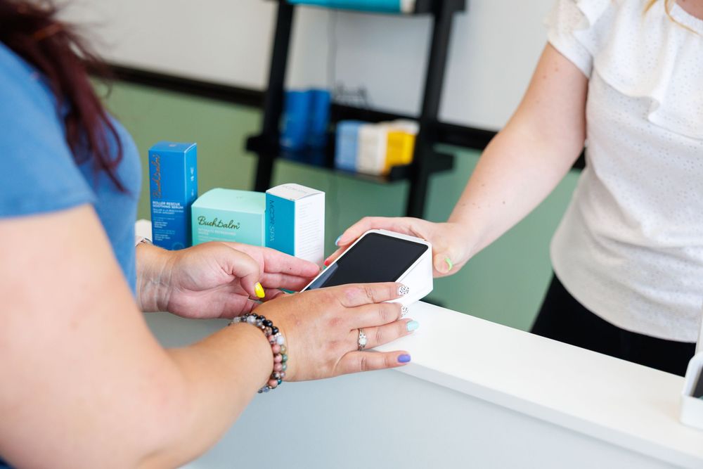 Customer makes a payment with a smartphone at a retail counter while wearing a bracelet.