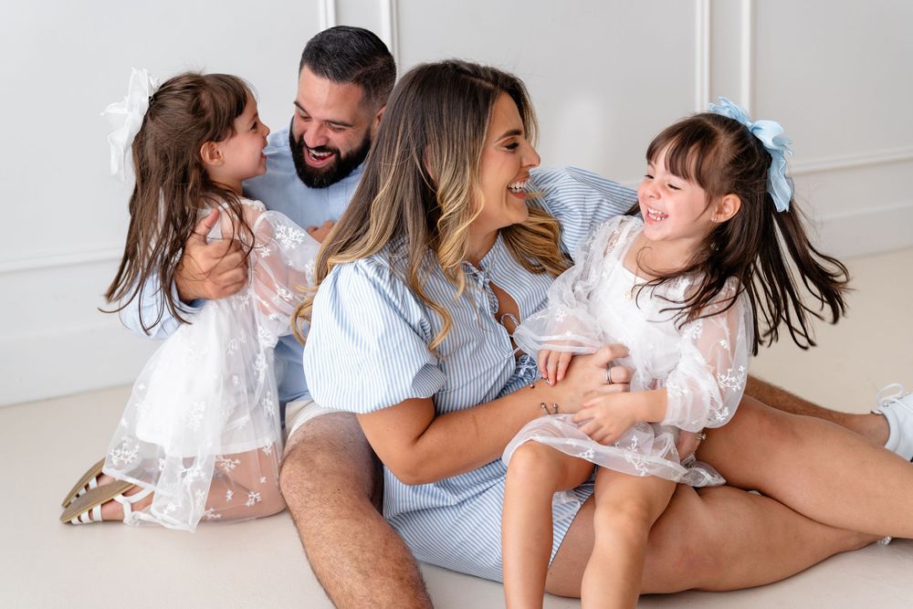 Joyful family moment captured on white backdrop while playing and laughing together.