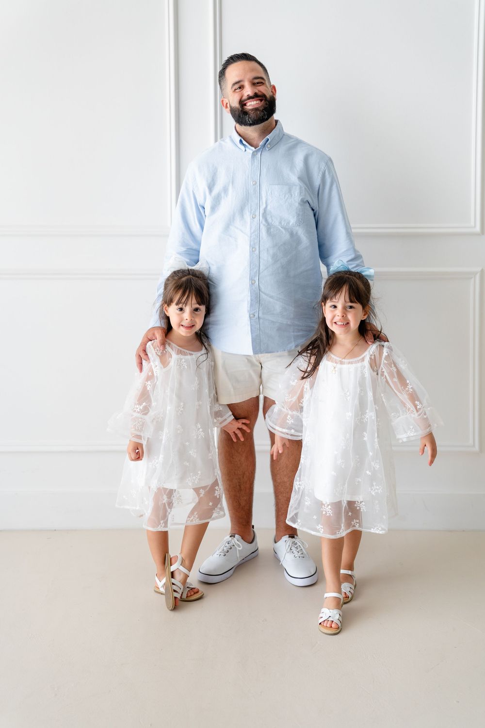 Parent and children in coordinated blue and white outfits pose together against a white wall.