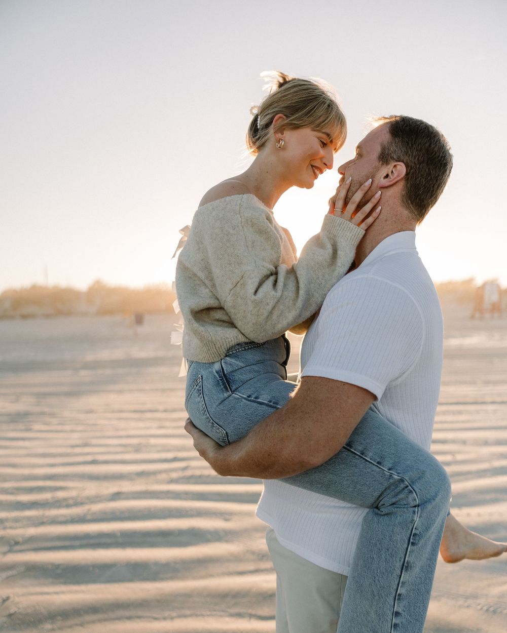 A playful moment between a couple on the beach as the sun sets behind them.
